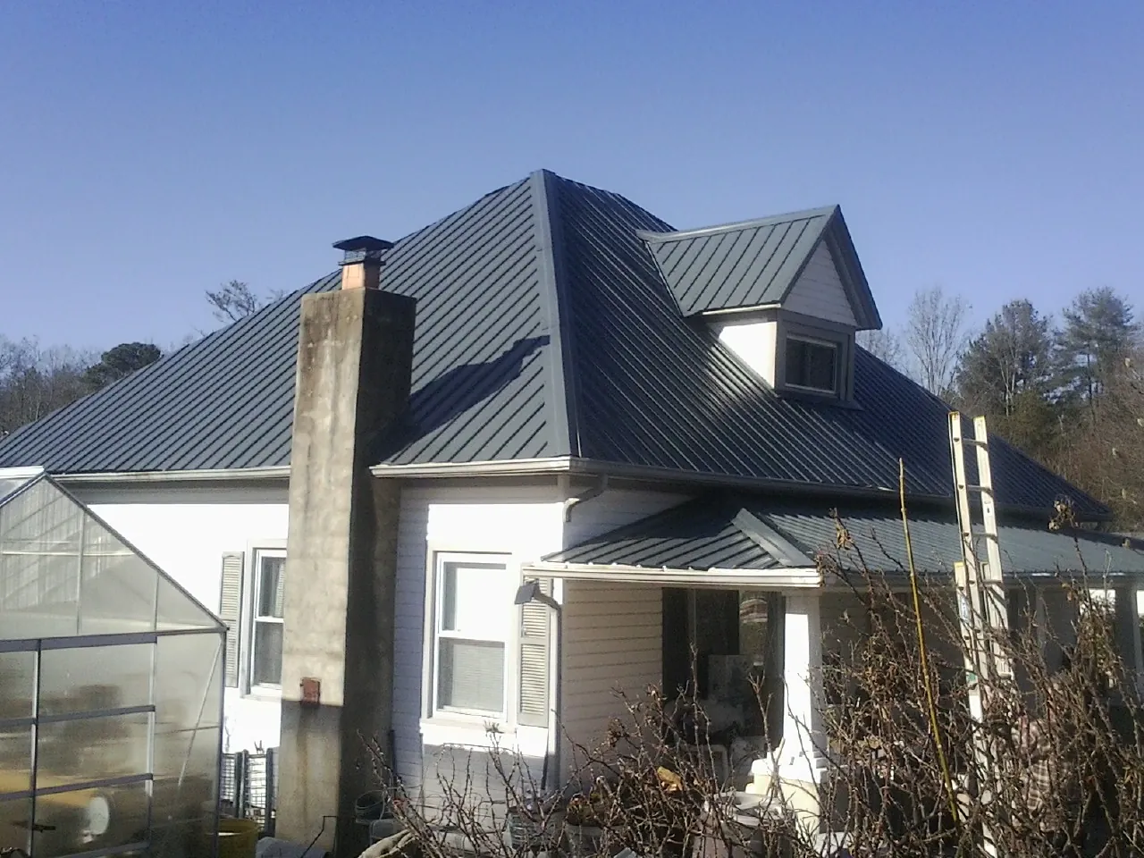 Dark blue standing seam metal roof on a white farmhouse with dormer — Slate & Tile Roof Repair by Roofing Brothers in Sagamore Beach