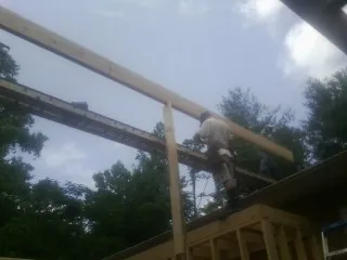 Carpenter setting a ridge beam over a new addition frame — Ice Dam Removal by Roofing Brothers in Sagamore Beach