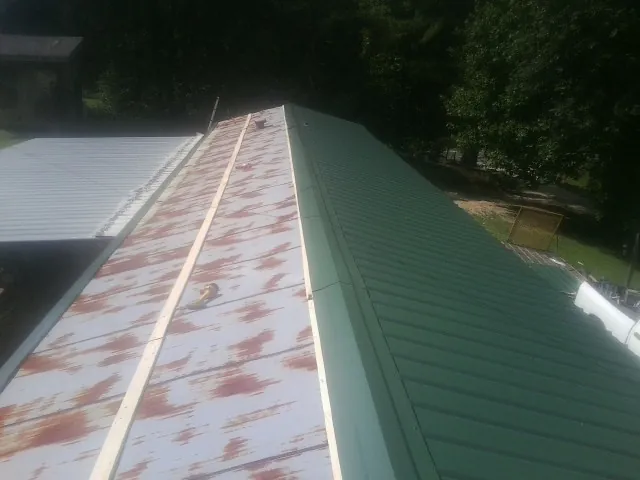 Old rusted panels beside newly installed green metal roofing — Wind Damage Roof Repair by Roofing Brothers in Sagamore Beach