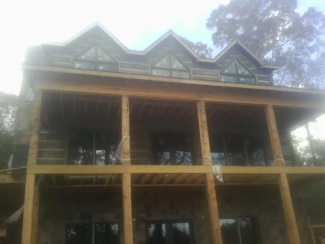 Dormers and porch framing on a large log home under construction — Roof Coating work by our crew in Sagamore Beach