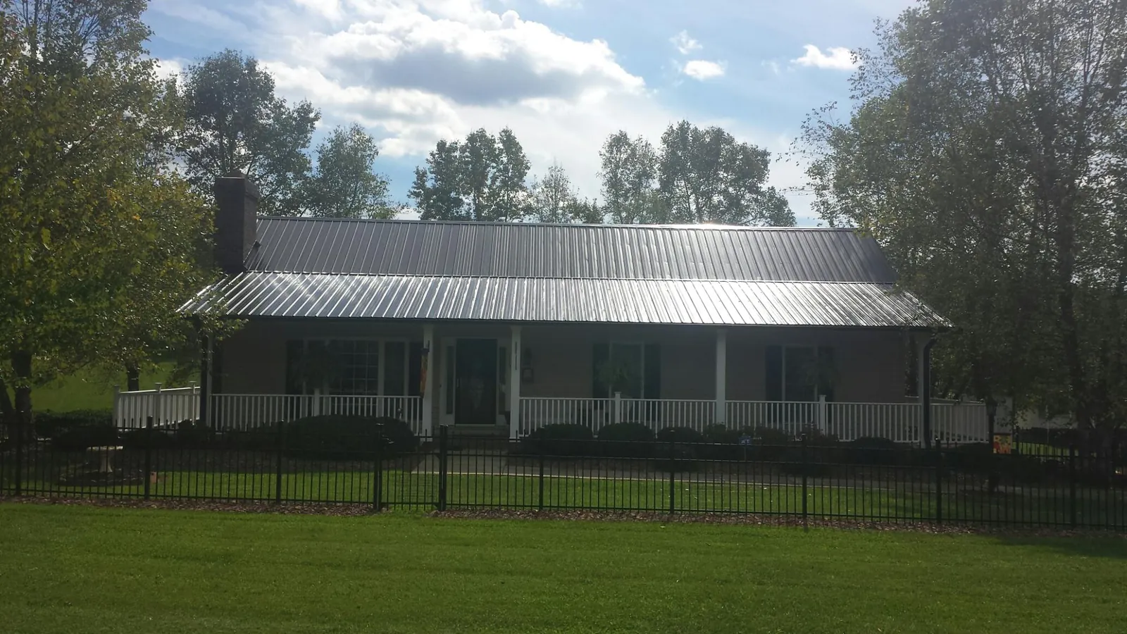 Gray metal roof on a brick ranch with a full width front porch — Gutter Guard Installation work by our crew in Sagamore Beach