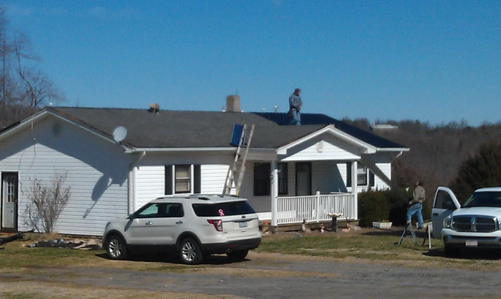 Roofers stripping shingles from a white ranch house roof in Sagamore Beach